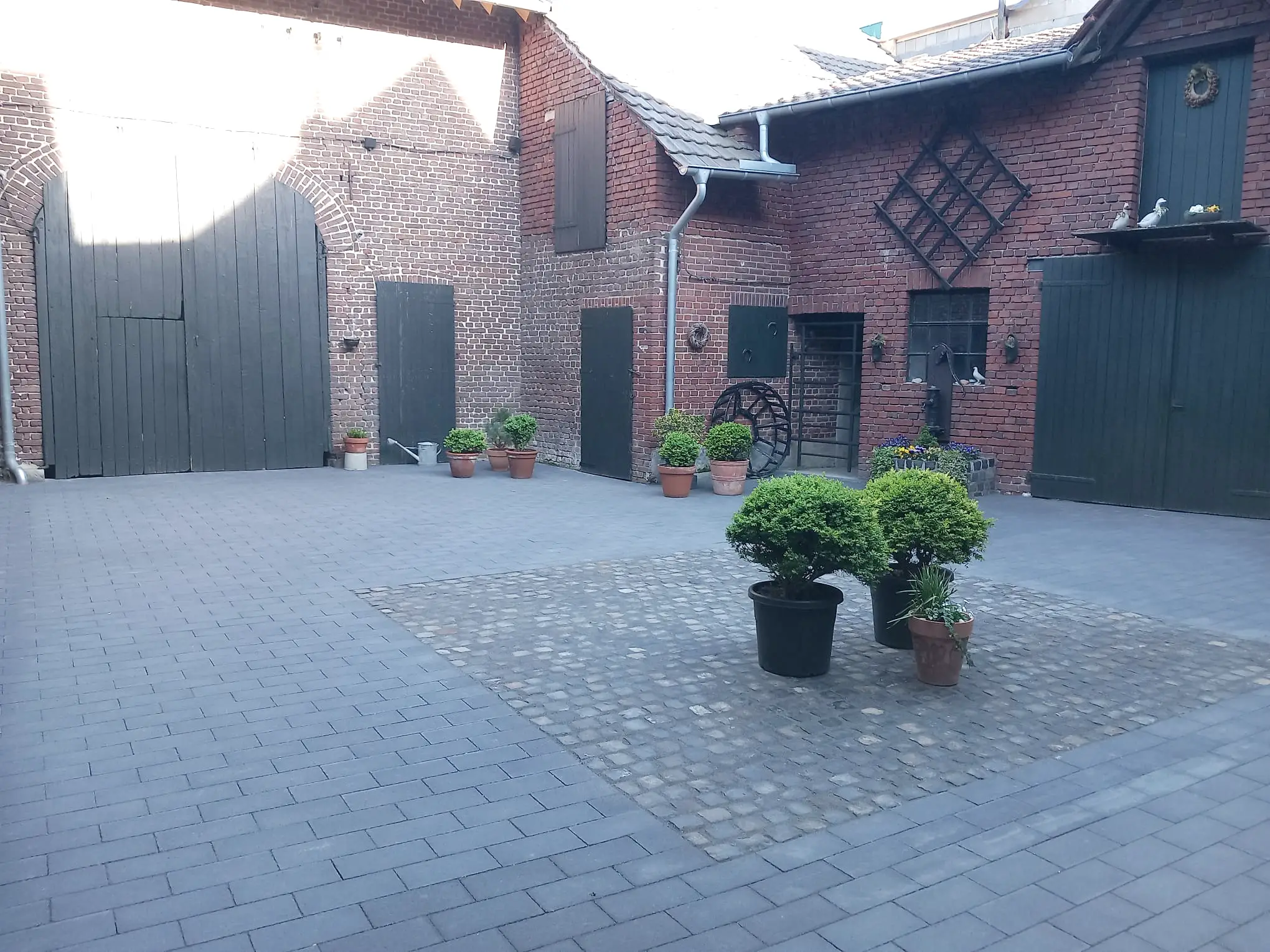 Fertig gepflasterter Innenhof mit Natursteinpflaster in der Mitte und Blumenkübeln zur Verschönerung