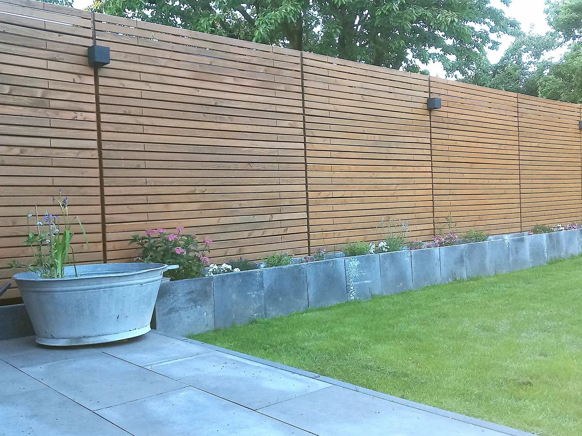 Gartenzaun mit Pflanzkübeln davor aus Stein